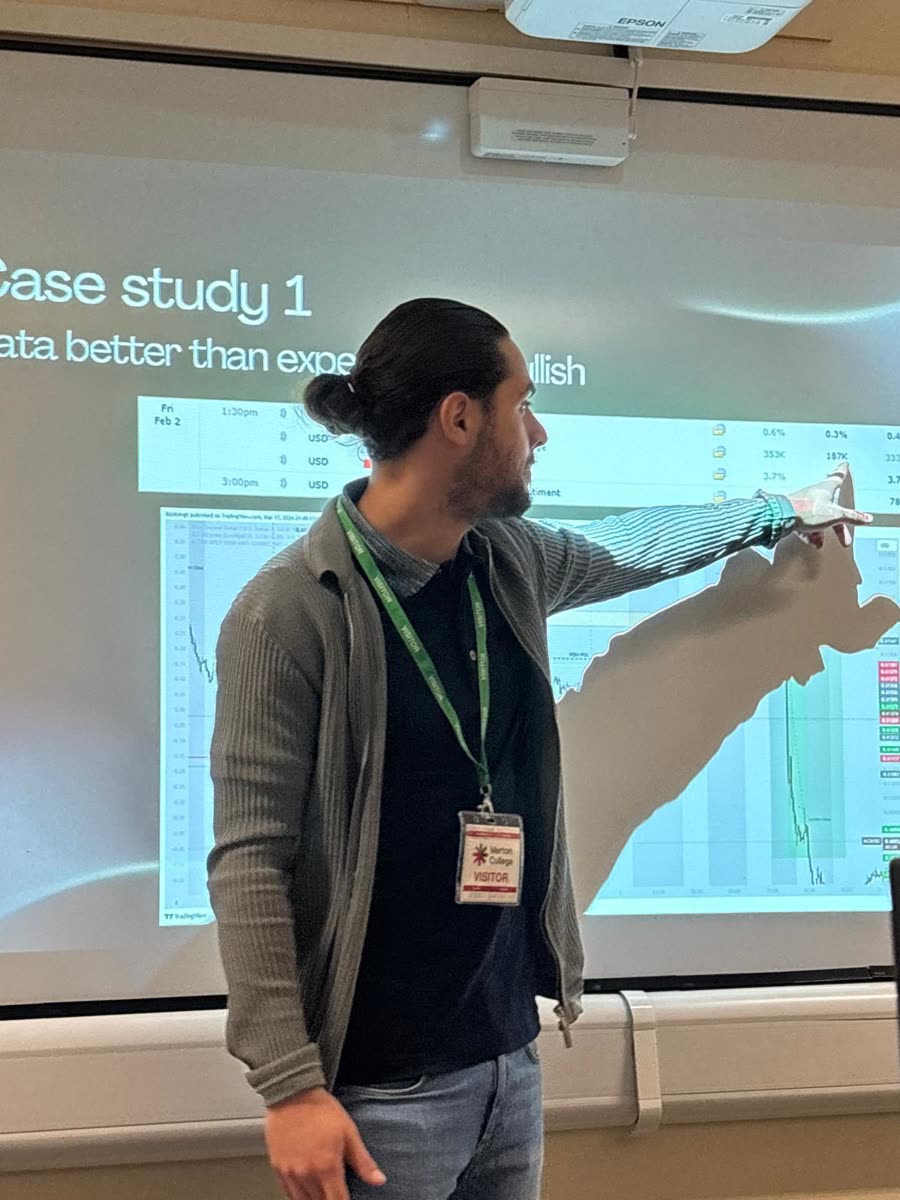 Mentor pointing at a live market chart during the Merton College seminar